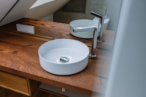 Modernes Waschbecken in Schalenform auf alter Holzplatte als Badgestaltungsidee.